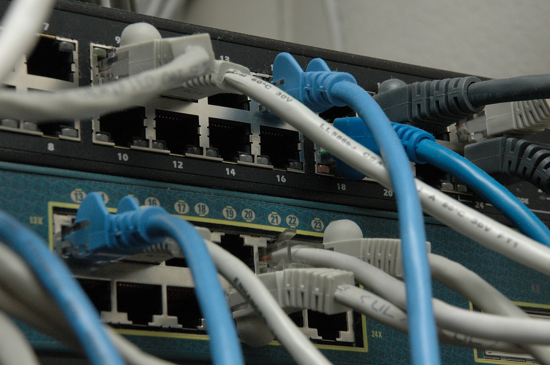 Stack of network switches with ethernet cables plugged into front ports